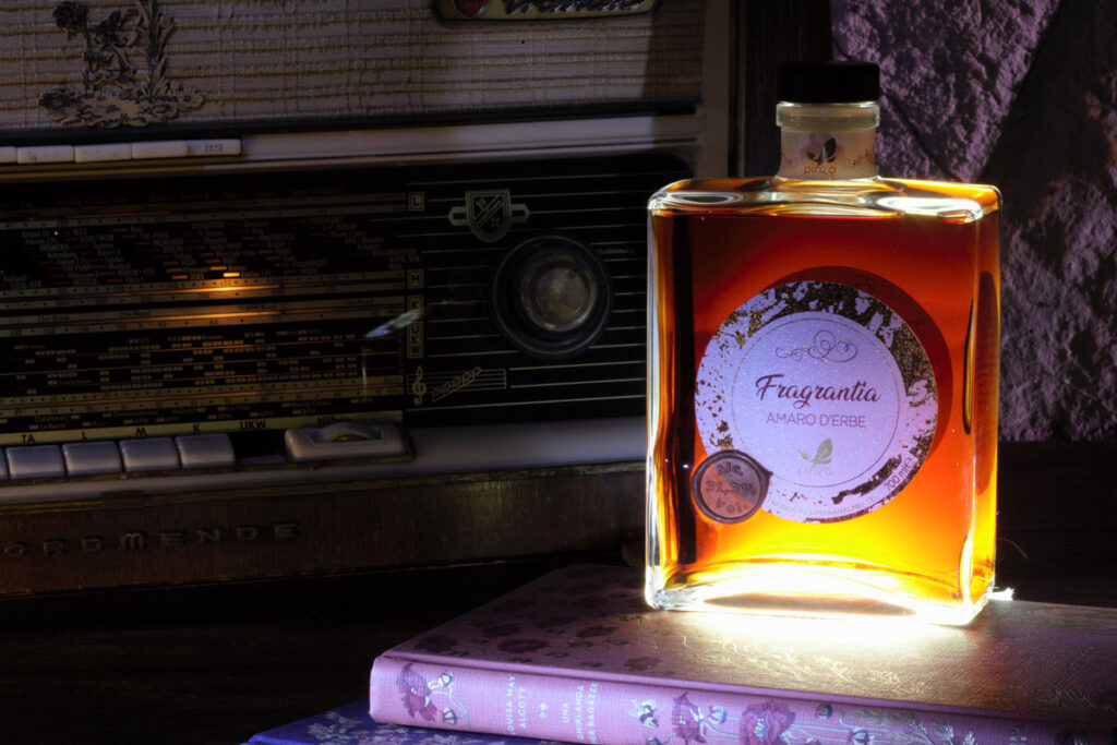 Eine Flasche Amaro Fragrantia auf Büchern neben einem Vintage Radioempfänger