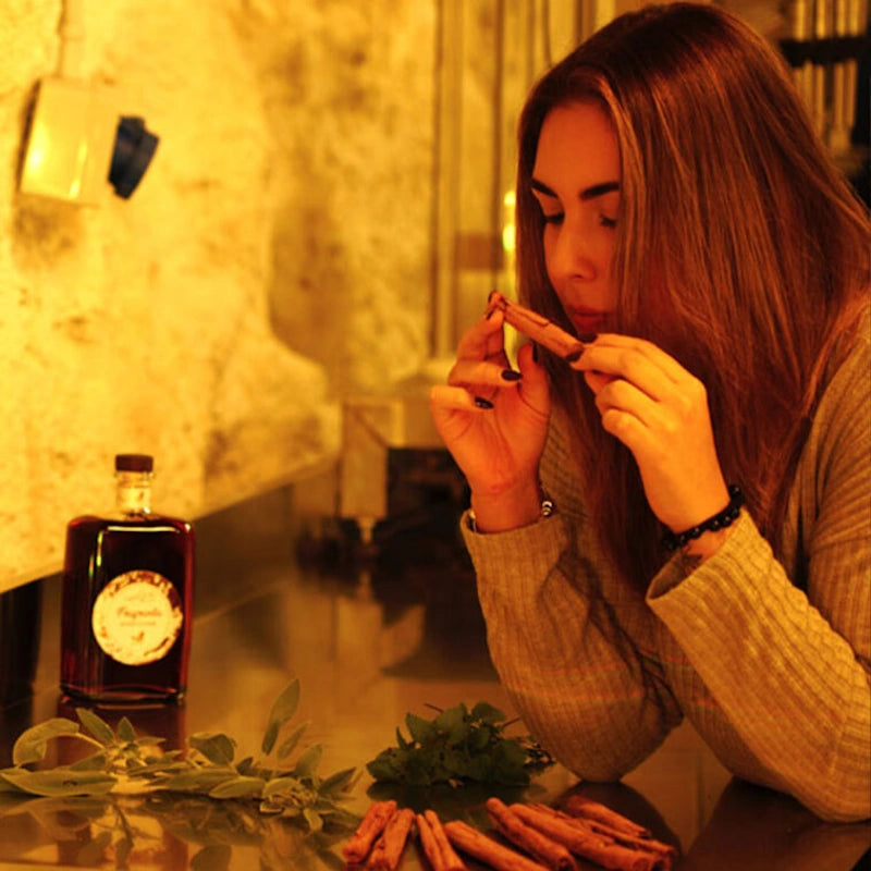 Frau riecht genussvoll an Kräutern aus denen der Amaro Fragrantia hergestellt wird