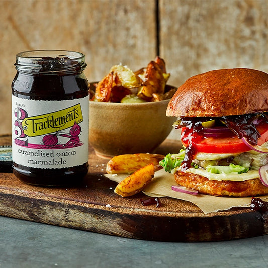 Burger und Wedges aus Holzplateau mit einem Glas karamellisierter Zwiebelmarmelade von Tracklements