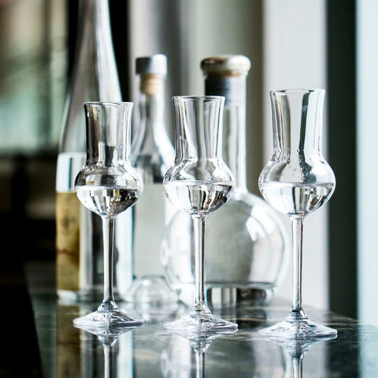 3 Grappagläser vor dem Hintergrund einiger Flaschen